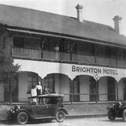Three gentlemen standing near two vintage cars outside the Brighton Hotel, Sandgate, ca. 1929